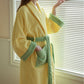 Yellow striped cotton terry bathrobe with green trim and the tie belt knotted at the waist