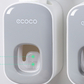 Close view of a grey toothpaste dispenser front showing the soft pad window where paste comes out