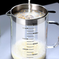 Liquid poured through the steel strainer into a glass jug marked from 400 ml to 1500 ml