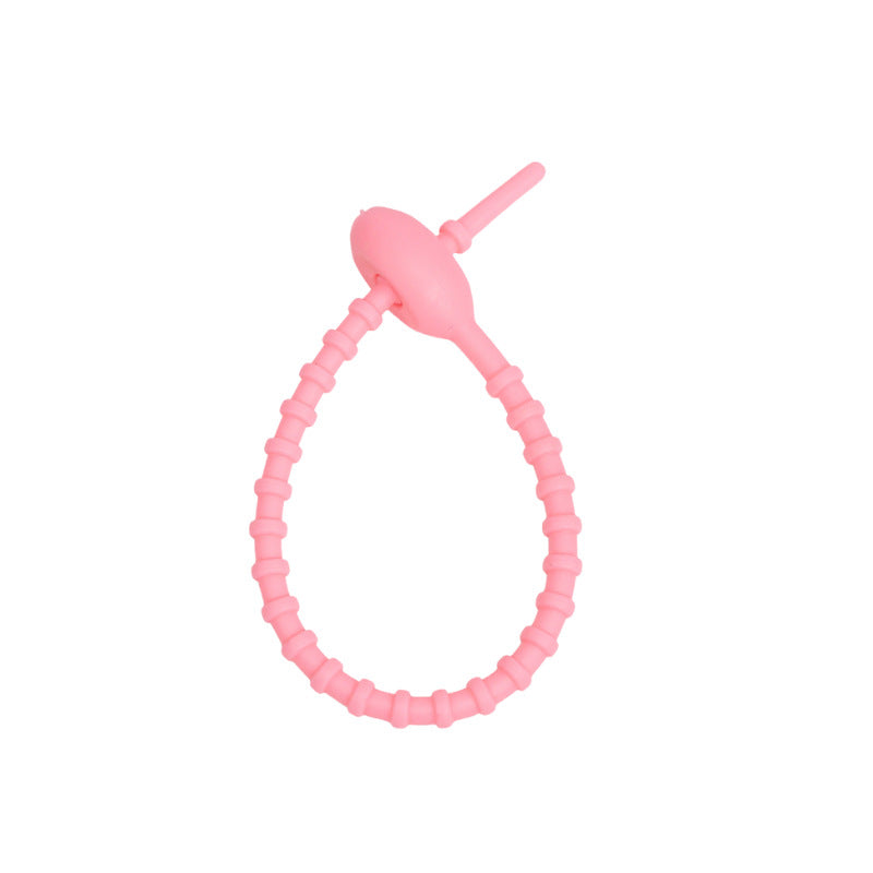 Soft silicone tadpole cable tie coiled into a loop to show the reusable cinch closure