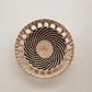 Woven straw wall disc with a wood-toned open rim hung on a plain wall