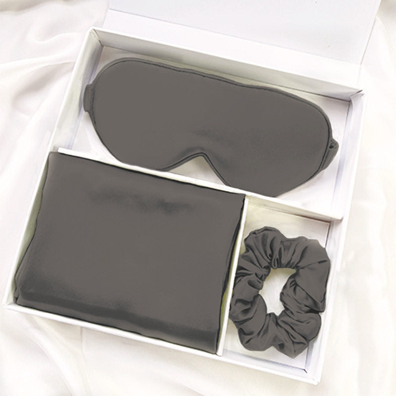 Silk gift box laid open showing pillowcase, eye mask and scrunchie in lotus pink