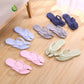 Five color pairs of folding flip flops arranged on a wood floor