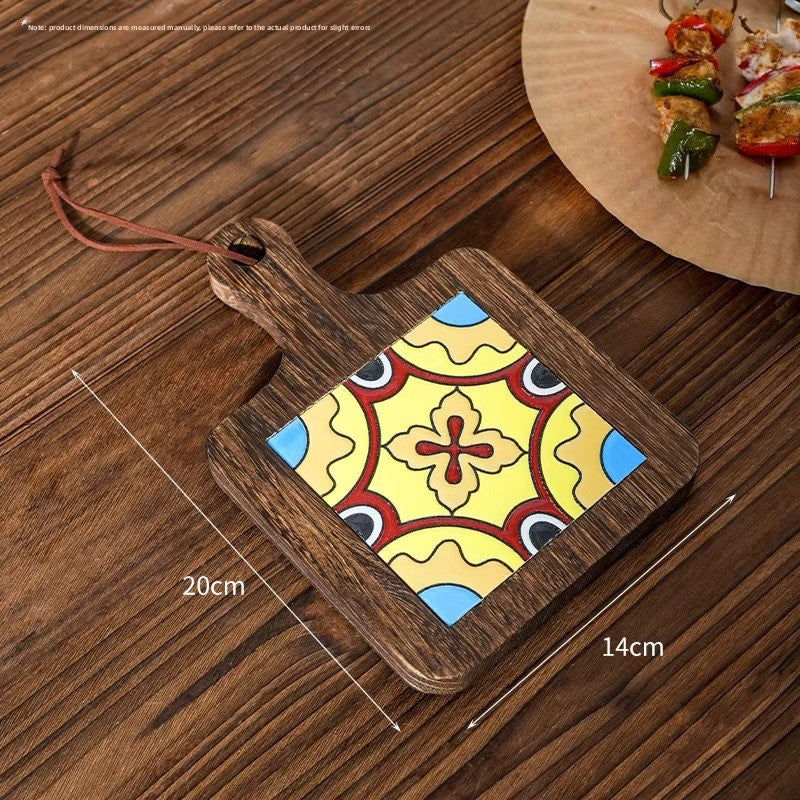 Wood trivet with a yellow and red quatrefoil tile on planks, marked 20 cm by 14 cm