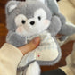 Grey plush husky squishy bean bag toy in one hand, rosy cheeks and a check dotted apron