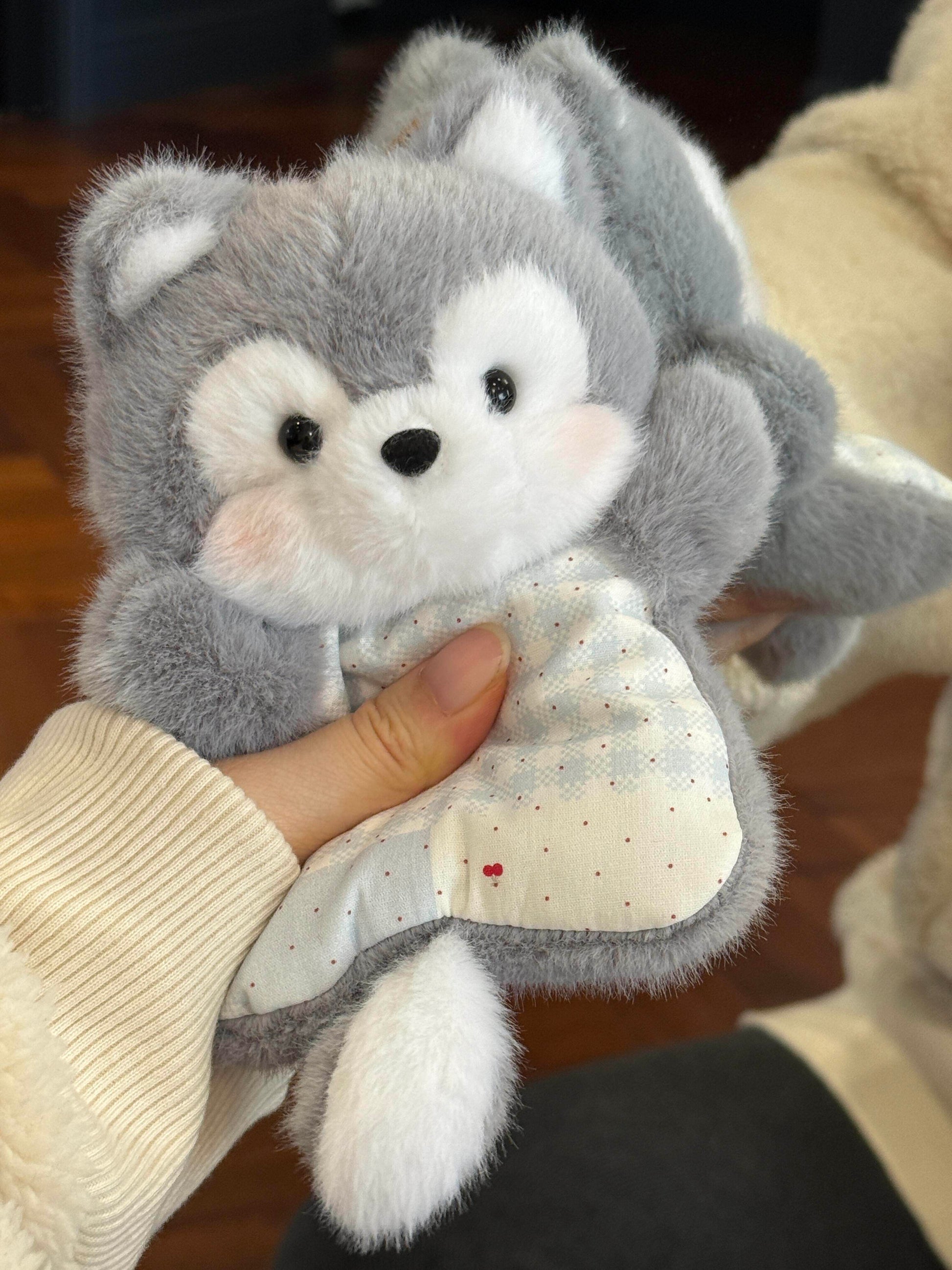Grey plush husky squishy bean bag toy in one hand, rosy cheeks and a check dotted apron