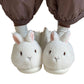 White bunny plush slippers worn with brown gathered trousers and gray socks on a plain white background