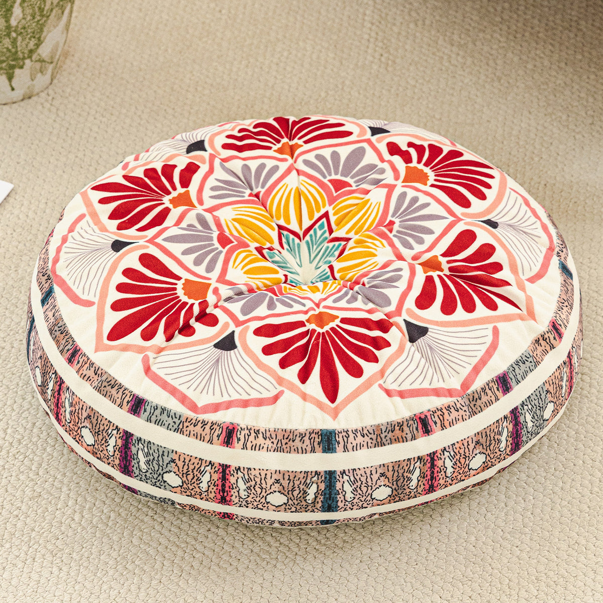 Round cushion with a red and pink lotus mandala print on a cream top and a pink striped side