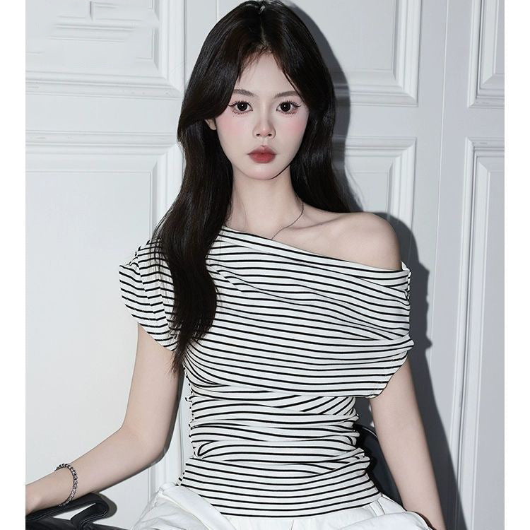 Woman in black and white striped off-shoulder knit top with one bare shoulder seated