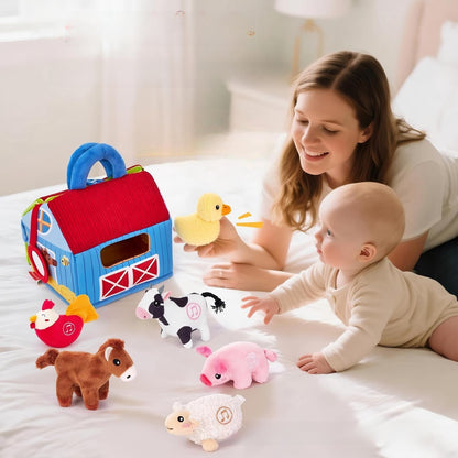 Blue and red cloth farm barn with plush hen, cow, duck, pig, horse and sheep beside a baby on a bed
