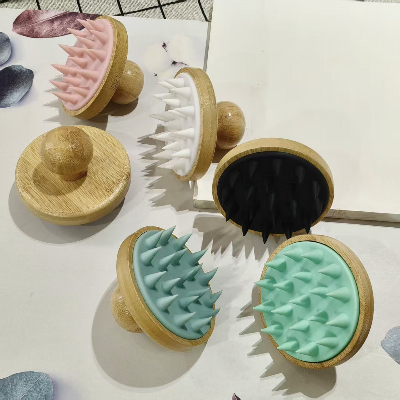 Group of round bamboo scalp brushes with flexible silicone bristles arranged on a white board