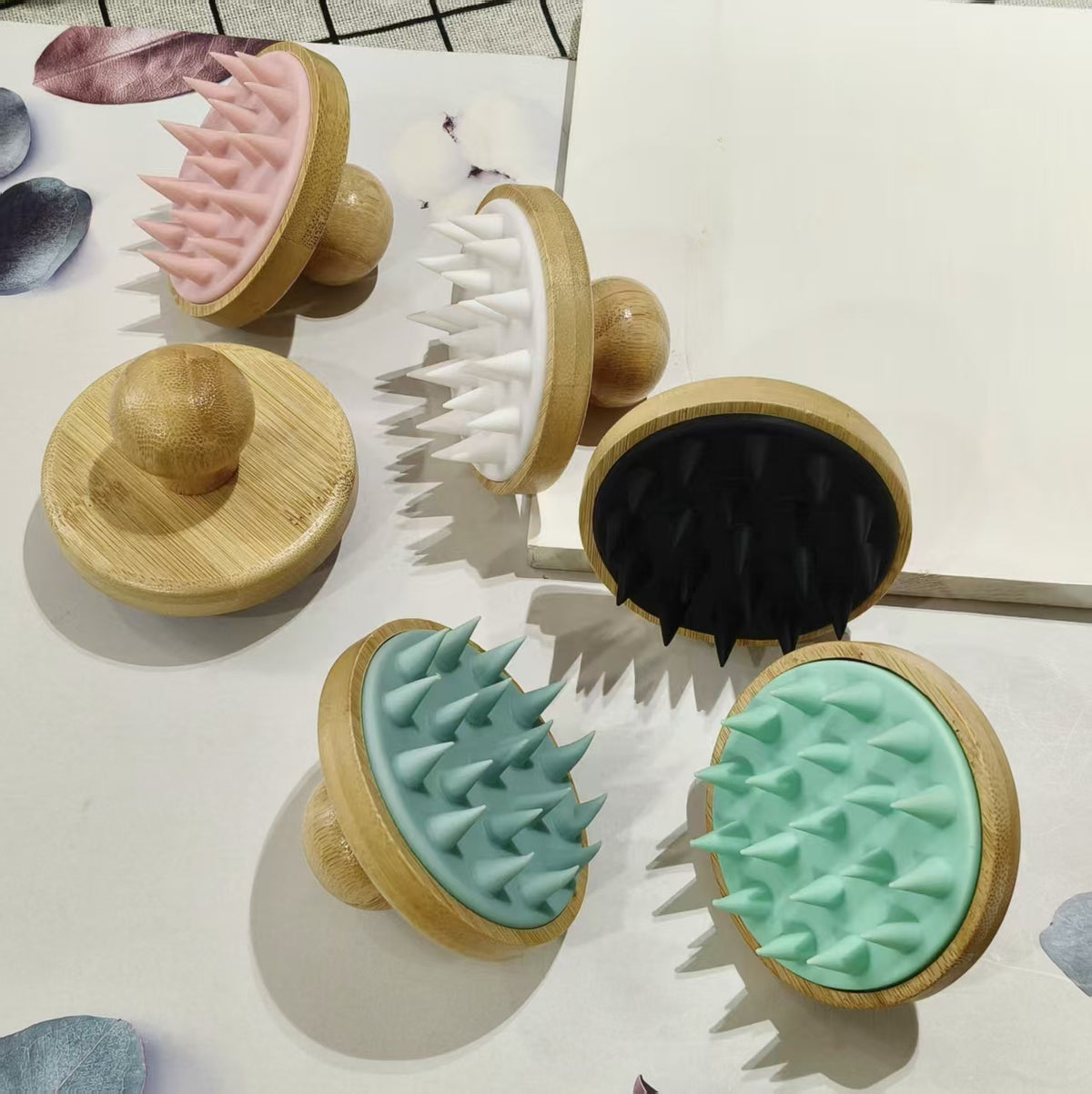 Group of round bamboo scalp brushes with flexible silicone bristles arranged on a white board