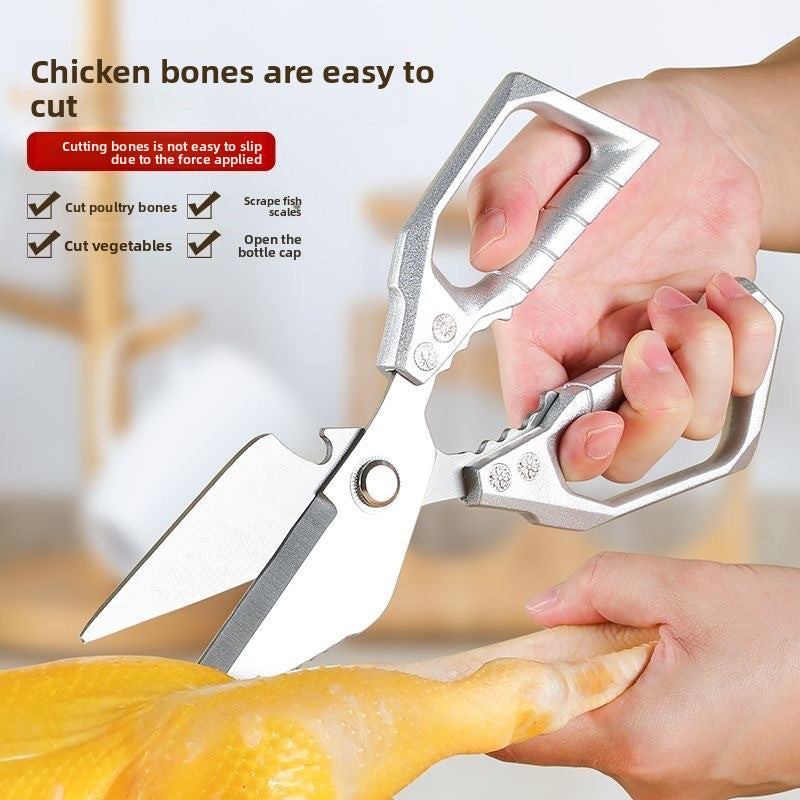 Silver stainless steel kitchen shears cutting a chicken leg with labeled uses around the blade