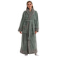 Woman wearing a long sage green flannel bathrobe with gray shawl collar, cuffs, pockets and hem, sage green variant