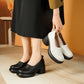 Woman holding off white platform heels while wearing black slip-on heels with a black skirt