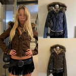 Woman in a brown short hooded jacket with a fur trimmed hood, black fringe skirt and braided belt in a hallway