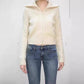 Woman wearing cream knit zip cardigan with wide ribbed collar and ribbed hem over blue jeans, front view