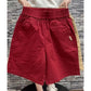 Burgundy high waist wide leg shorts worn casually at mid thigh length