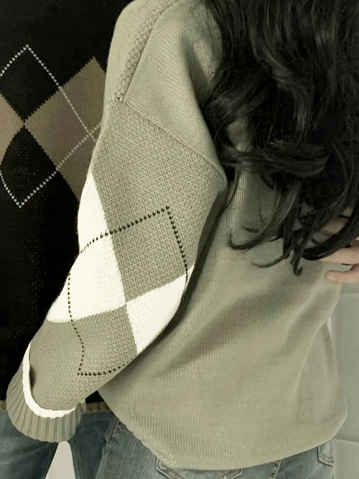 Matcha green sweater with a cream diamond sleeve seen from behind, black and tan argyle sweater of another colourway at left