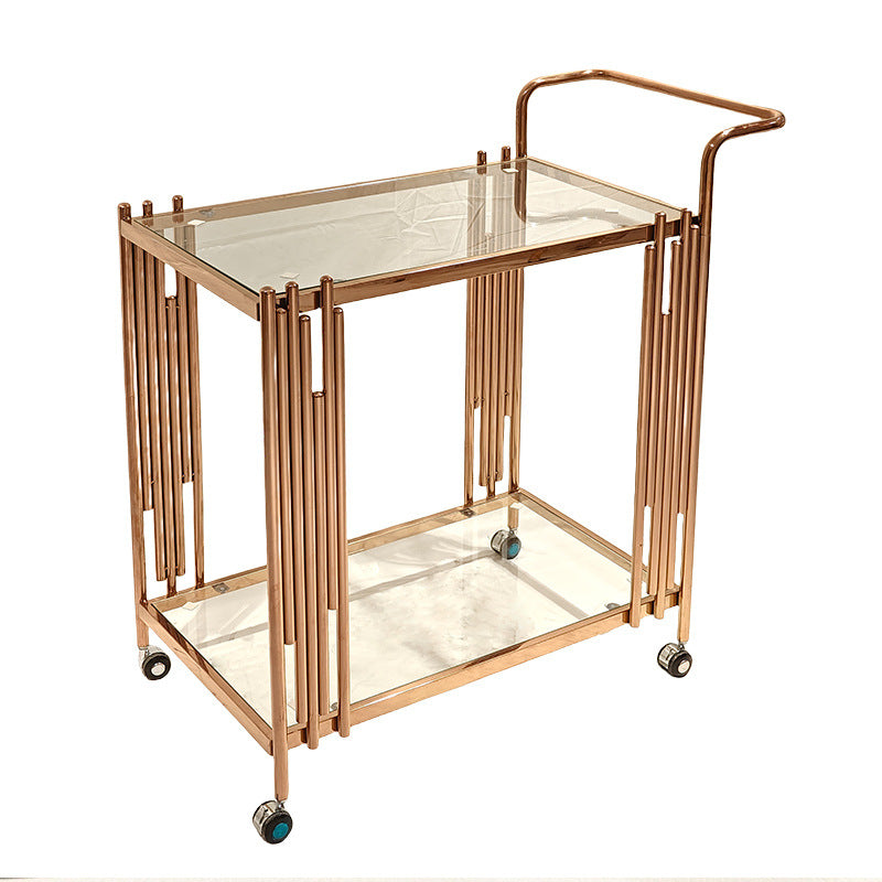 Close view of a swivel caster wheel under the gold toned stainless steel serving cart