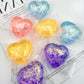 Aurora glitter hearts individually twisted into clear film, mixed pastel colours on a page