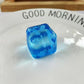 Blue gel snowflake ice cube squishy toy squeezed between fingers on a light backdrop