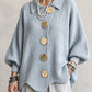 Woman in a light blue ribbed knit top with lantern sleeves and large metal buttons, front view