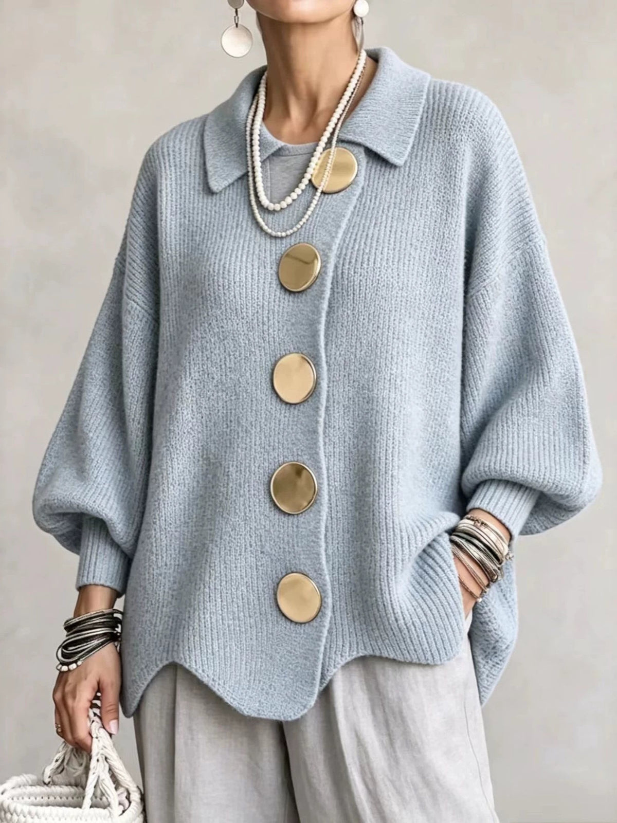 Woman in a light blue ribbed knit top with lantern sleeves and large metal buttons, front view