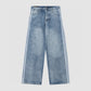 Angled shot of baggy washed denim jeans with zip fly, belt loops and side stripes