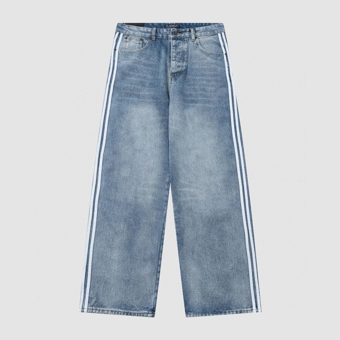 Angled shot of baggy washed denim jeans with zip fly, belt loops and side stripes