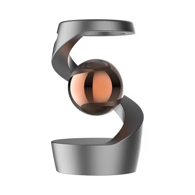 Metal desk toy with a bead held aloft by magnets beside a laptop