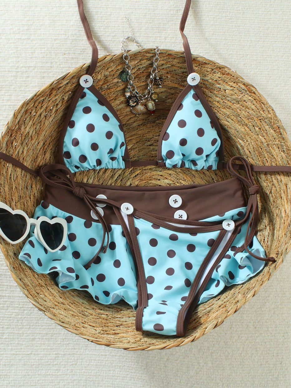 Polka dot bikini set flat on a straw hat, triangle top above the tie side brief with white buttons