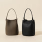 Leather bucket bag held in hand showing the compact 15x13x19cm size