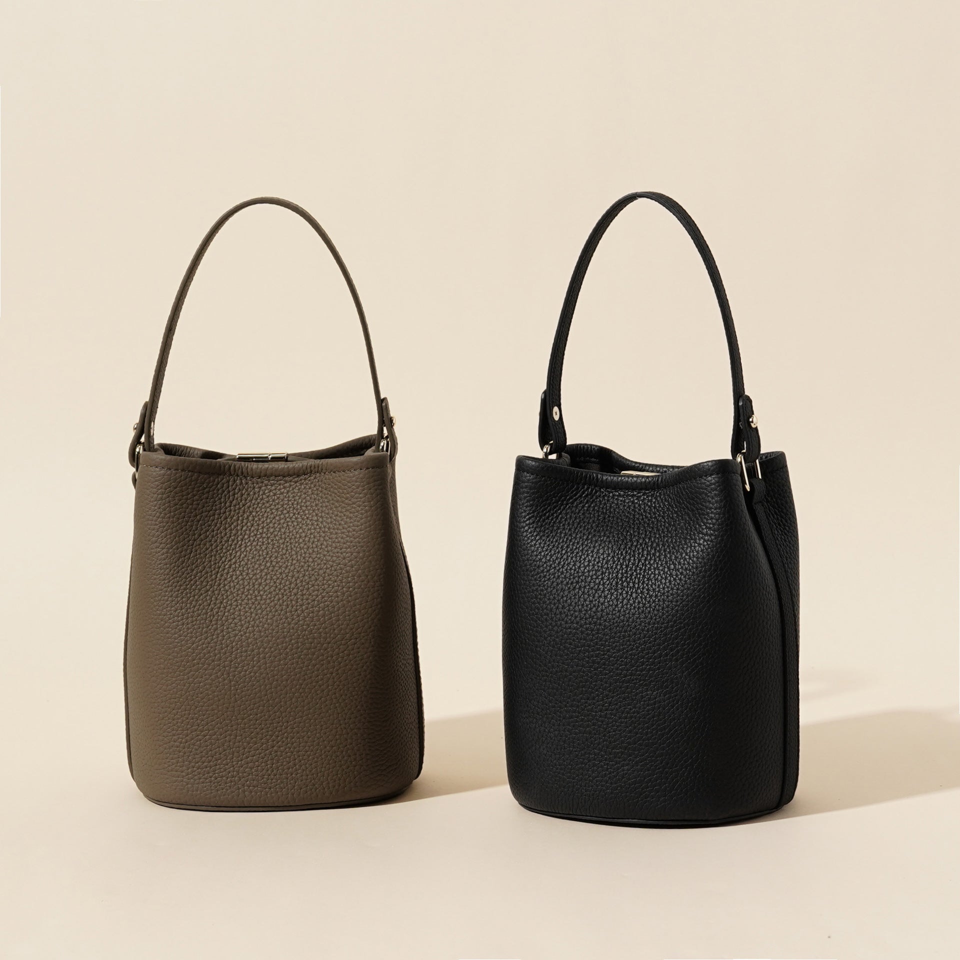 Leather bucket bag held in hand showing the compact 15x13x19cm size