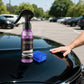 Purple coating spray and a folded blue microfibre cloth on a black car bonnet in a car park