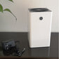 White HD-68D dehumidifier on a dark table beside its black power adapter with a UK style plug