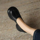 Top view of a black PU slip-on pump with stitched toe seam, rounded toe and platform edge on a woven rug
