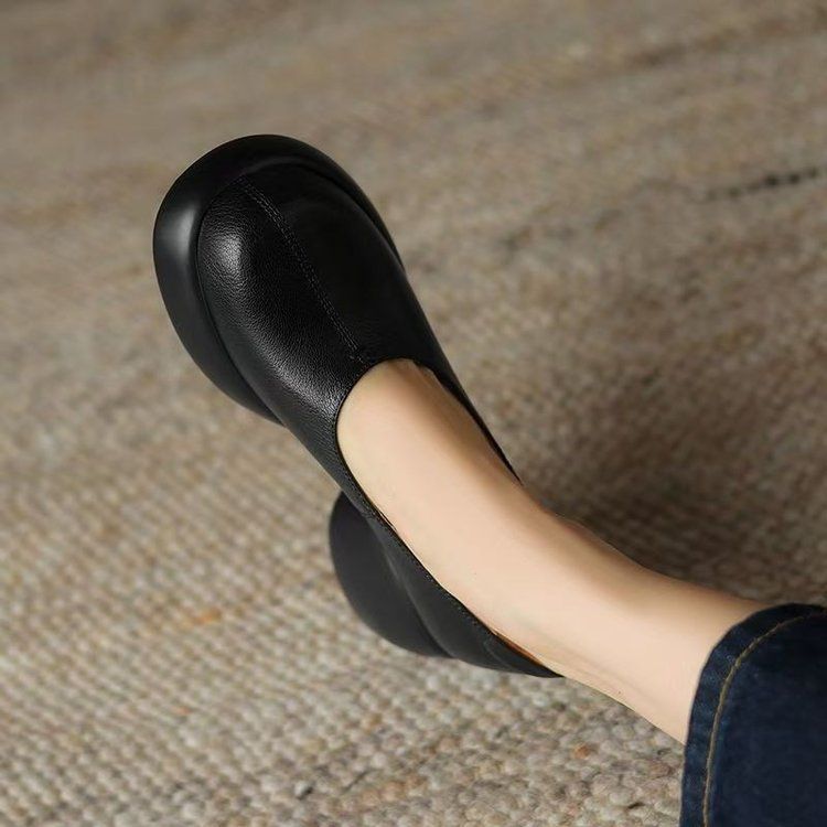 Top view of a black PU slip-on pump with stitched toe seam, rounded toe and platform edge on a woven rug