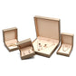 Open champagne gold jewelry boxes holding earrings, a bracelet and a necklace set