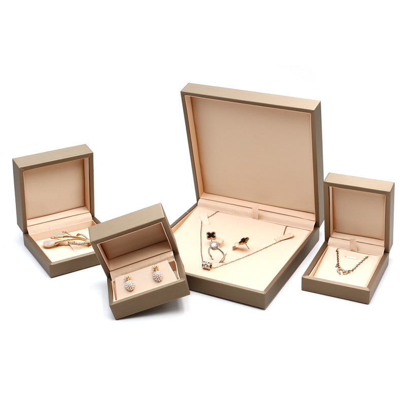 Open champagne gold jewelry boxes holding earrings, a bracelet and a necklace set