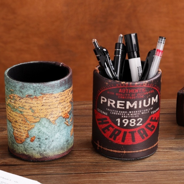 Round vintage pen cups with a world map and a Premium 1982 Heritage print holding pens on a wooden table