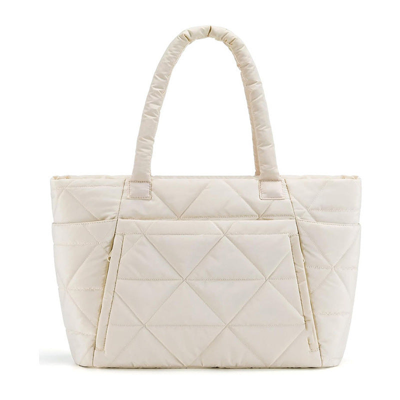 Cream beige padded quilted nylon shoulder bag with rounded handles on white