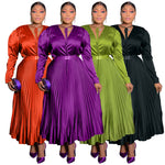 Four pleated maxi dresses with belts lined up in orange, purple, olive green and black