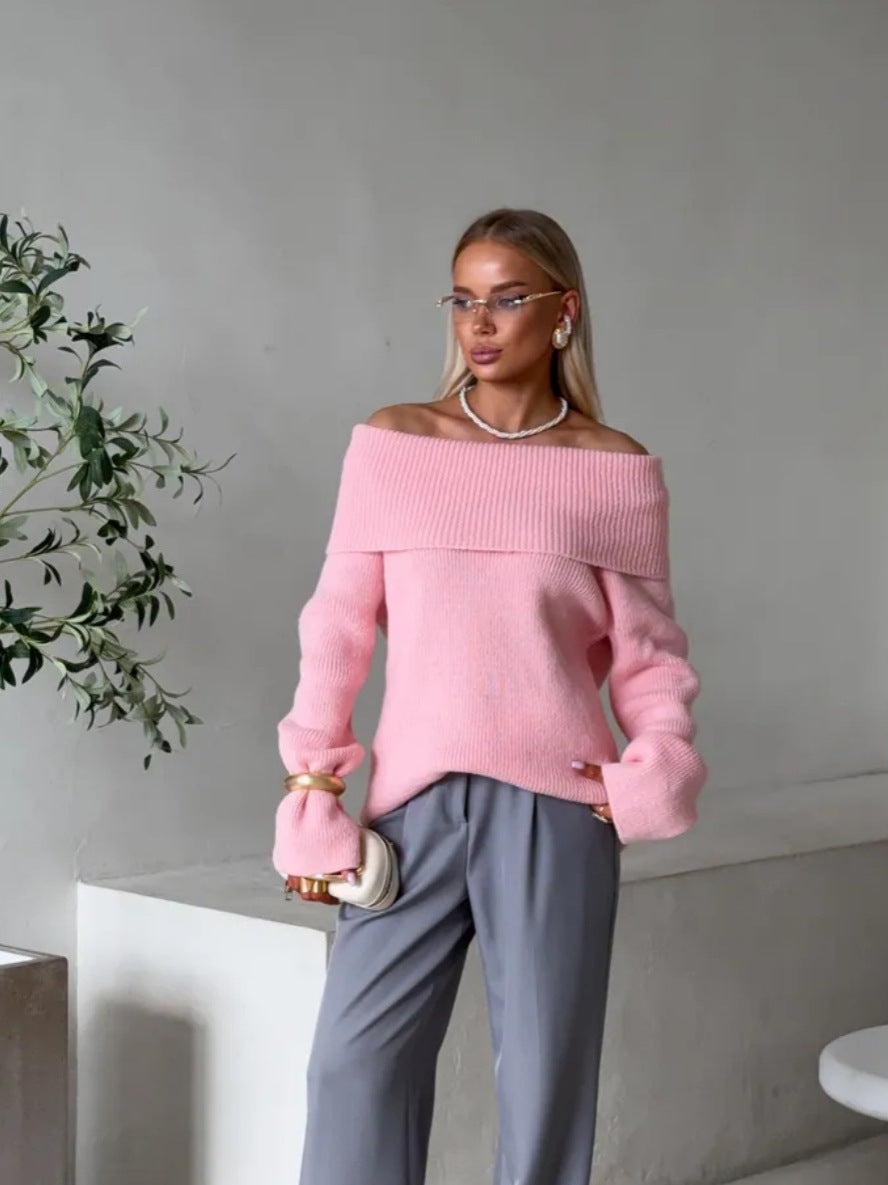 Pink off-shoulder fold-over knit sweater worn with grey trousers and a pearl necklace