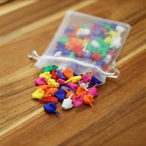 Sheer white drawstring pouch spilling assorted PVC middle finger novelty figures onto a wooden table