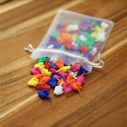 Sheer white drawstring pouch spilling assorted PVC middle finger novelty figures onto a wooden table