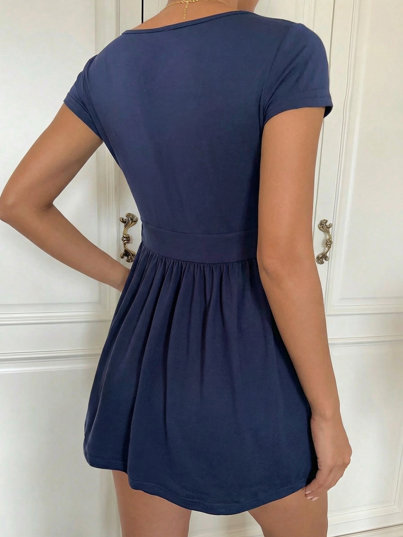 Navy babydoll top showing the surplice V-neck and gathered empire waist on a model