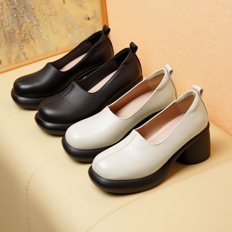 Black and off white leather slip-on platform block heel shoes on a cream bench