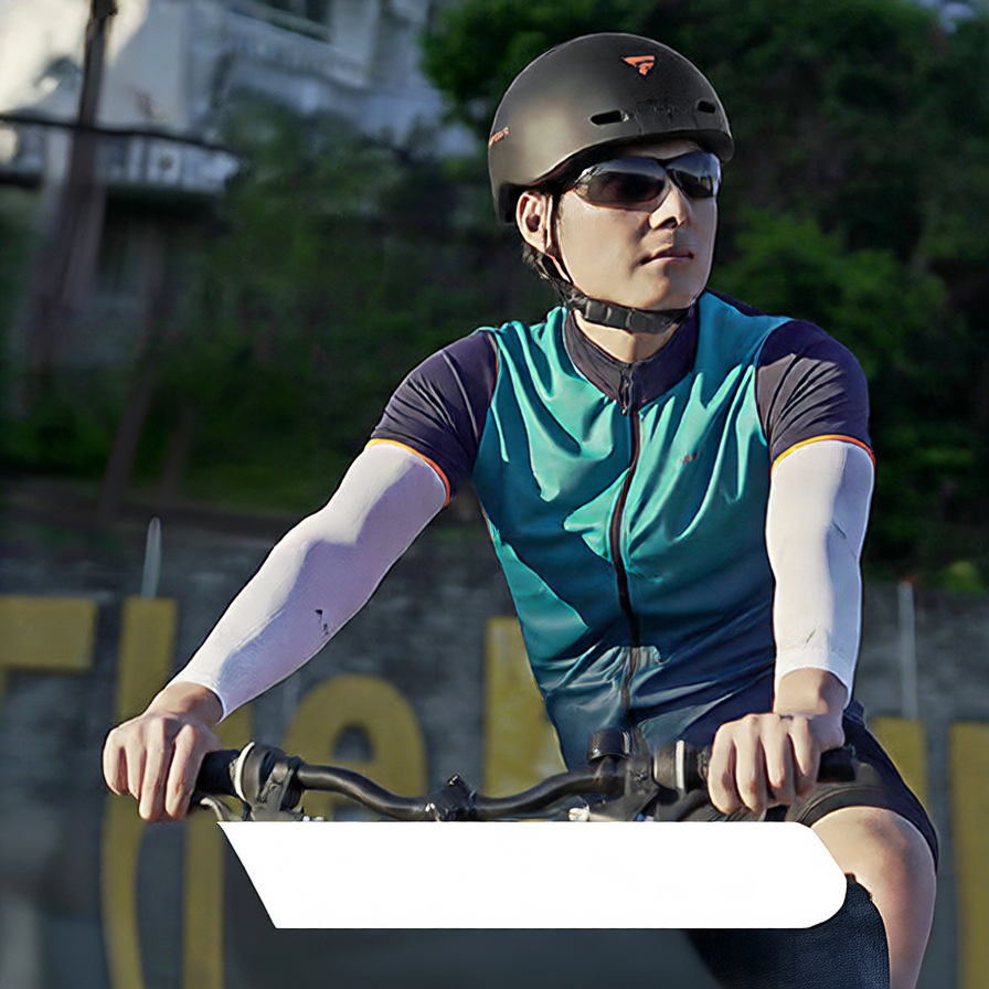 Cyclist wearing a black Foxwear camera helmet and sunglasses on a bicycle outdoors