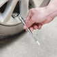 Hand pressing the pencil tire gauge onto a car valve, white scale stick pushed out of the barrel